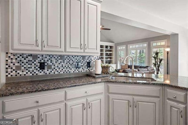 kitchen featuring sink, white cabinets, backsplash, and dark stone counters