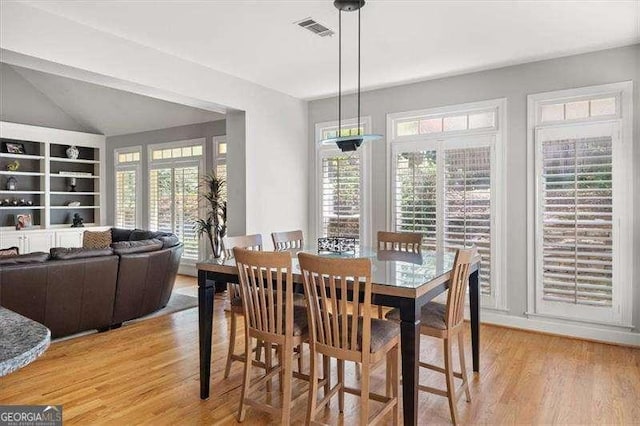 dining room with lofted ceiling and light hardwood / wood-style flooring