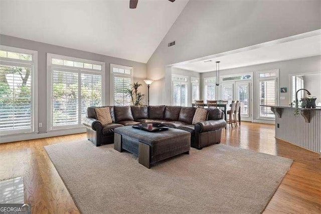 living room with light hardwood / wood-style flooring, high vaulted ceiling, and ceiling fan