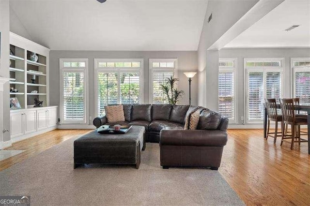 living room featuring lofted ceiling and light hardwood / wood-style floors