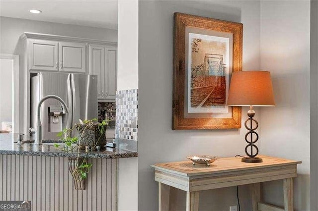 kitchen featuring white cabinetry, stainless steel fridge, dark stone counters, and tasteful backsplash