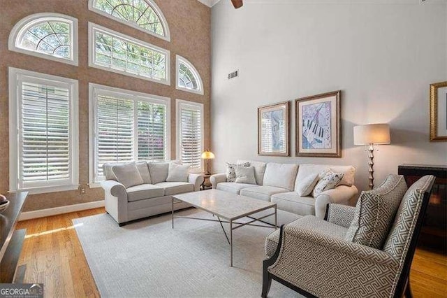 living room featuring a high ceiling, a healthy amount of sunlight, and light wood-type flooring