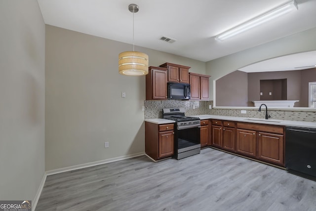 kitchen featuring sink, black appliances, tasteful backsplash, and hanging light fixtures