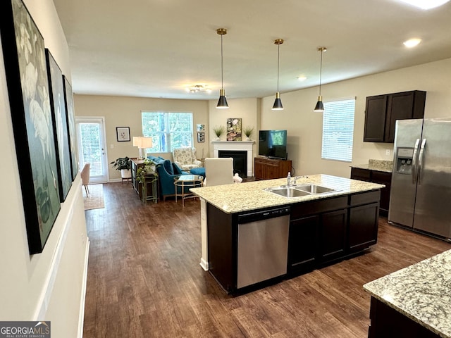 kitchen with sink, dark brown cabinets, hanging light fixtures, a center island with sink, and stainless steel appliances