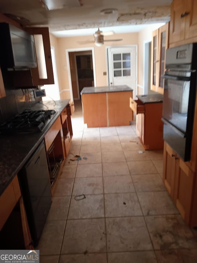 kitchen featuring a kitchen island, stainless steel gas stovetop, oven, light tile patterned floors, and ceiling fan