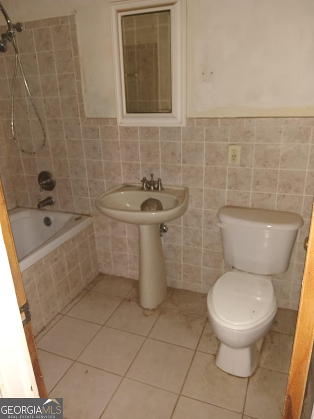 bathroom featuring tile patterned flooring, tiled shower / bath, tile walls, and toilet