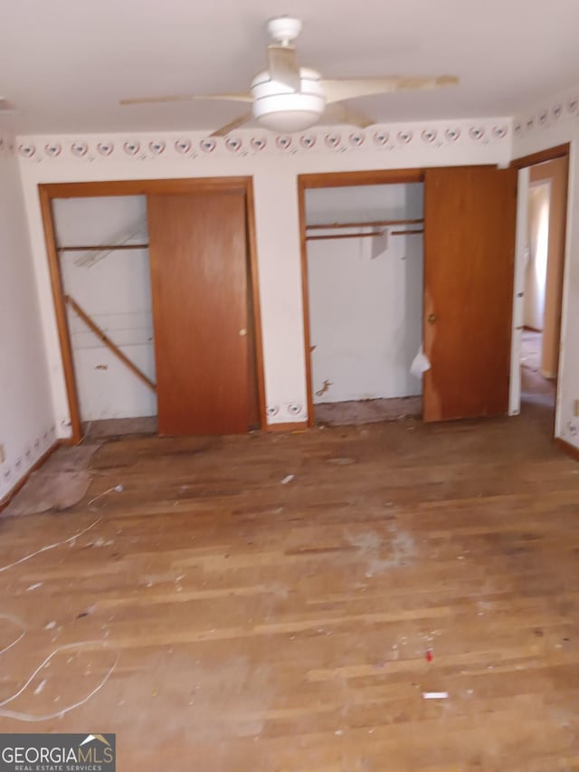 unfurnished bedroom with multiple closets and wood-type flooring