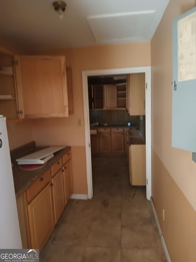 kitchen featuring backsplash, light brown cabinets, and white refrigerator