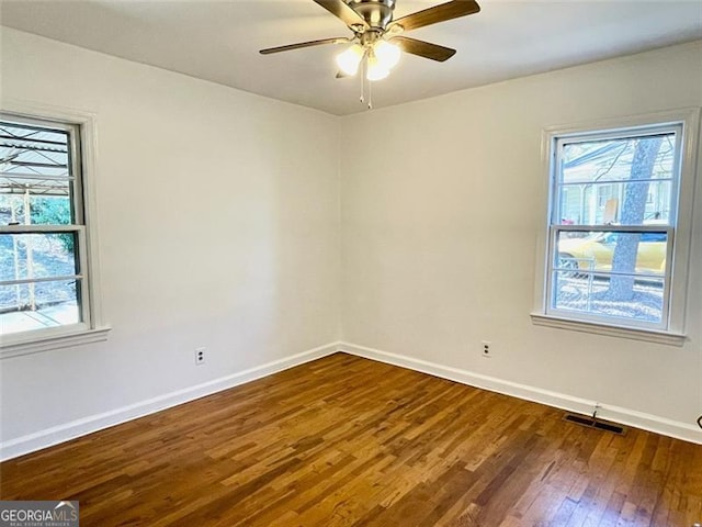 spare room featuring ceiling fan, a healthy amount of sunlight, and dark hardwood / wood-style flooring