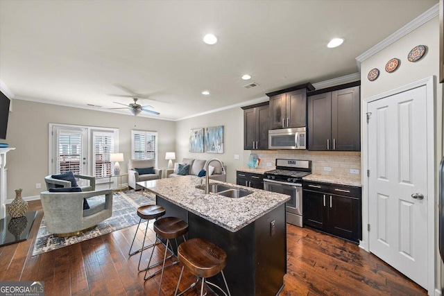 kitchen featuring sink, dark hardwood / wood-style flooring, a kitchen island with sink, light stone counters, and stainless steel appliances