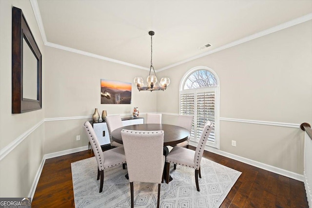 dining area featuring dark hardwood / wood-style flooring, ornamental molding, and an inviting chandelier