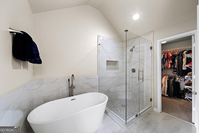 bathroom with lofted ceiling, independent shower and bath, and tile walls