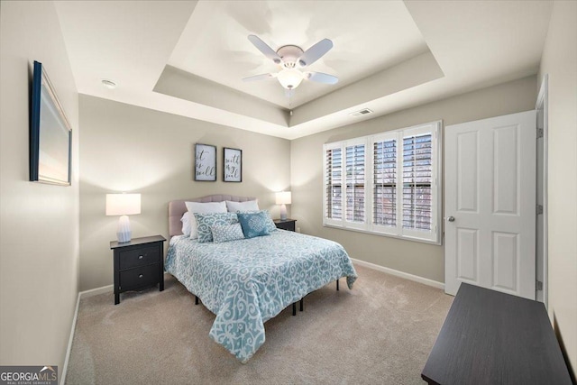 carpeted bedroom featuring a tray ceiling and ceiling fan