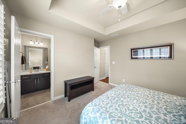 carpeted bedroom featuring a raised ceiling, sink, connected bathroom, and ceiling fan