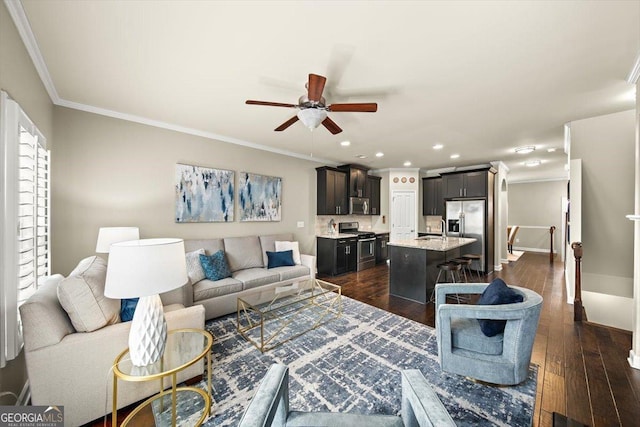 living room featuring sink, dark wood-type flooring, ornamental molding, and ceiling fan