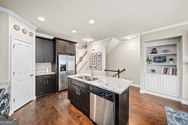 kitchen with sink, light stone counters, appliances with stainless steel finishes, dark hardwood / wood-style floors, and a kitchen island with sink