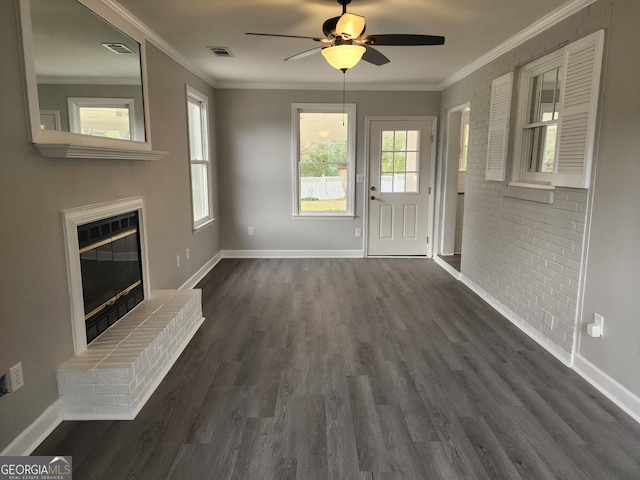 unfurnished living room with dark hardwood / wood-style flooring, crown molding, ceiling fan, and brick wall