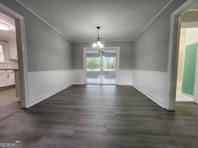 unfurnished dining area featuring an inviting chandelier, ornamental molding, and dark hardwood / wood-style flooring