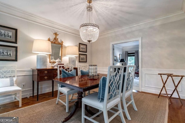 dining area with an inviting chandelier, hardwood / wood-style floors, and crown molding