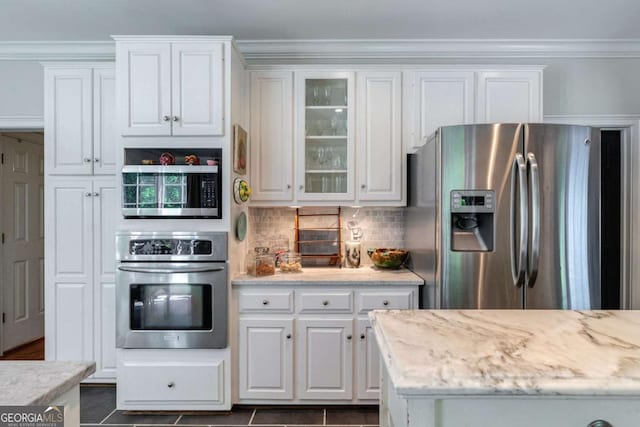 kitchen with white cabinetry, tasteful backsplash, light stone counters, ornamental molding, and stainless steel appliances