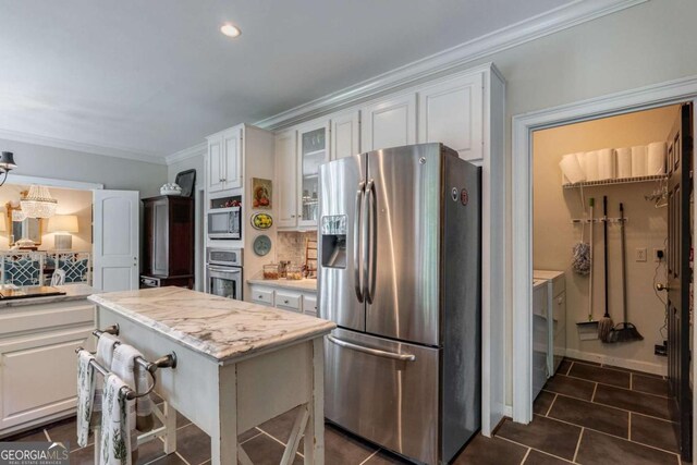 kitchen with white cabinetry, crown molding, a center island, appliances with stainless steel finishes, and backsplash