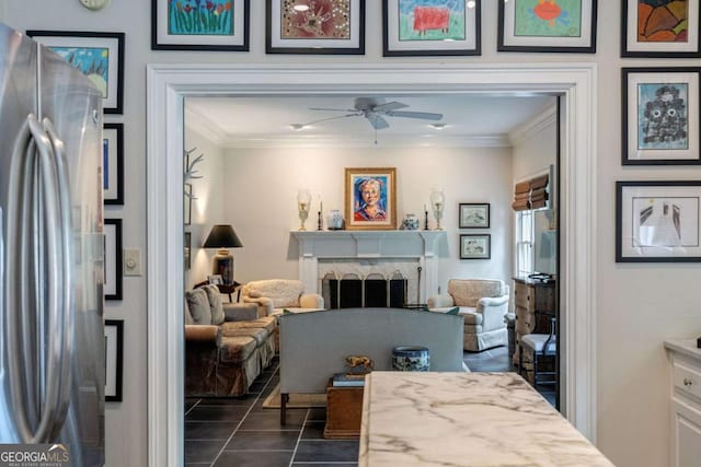 living room featuring crown molding, ceiling fan, and dark tile patterned floors