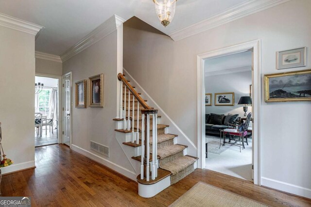 staircase with crown molding and wood-type flooring