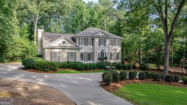 colonial-style house featuring a front lawn