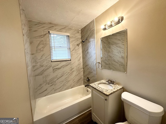 full bathroom with tiled shower / bath, vanity, toilet, and a textured ceiling