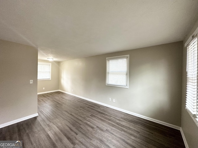 empty room featuring dark hardwood / wood-style flooring, a textured ceiling, and a wealth of natural light