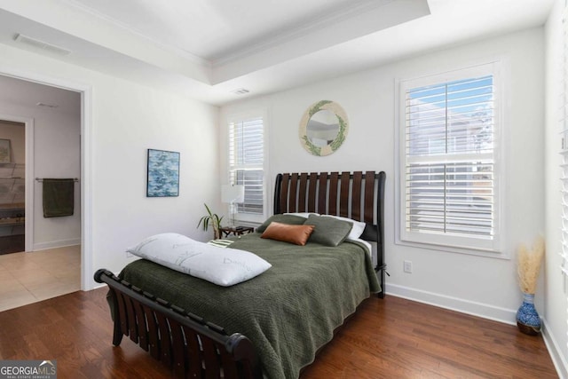 bedroom featuring a raised ceiling, ornamental molding, and dark hardwood / wood-style floors