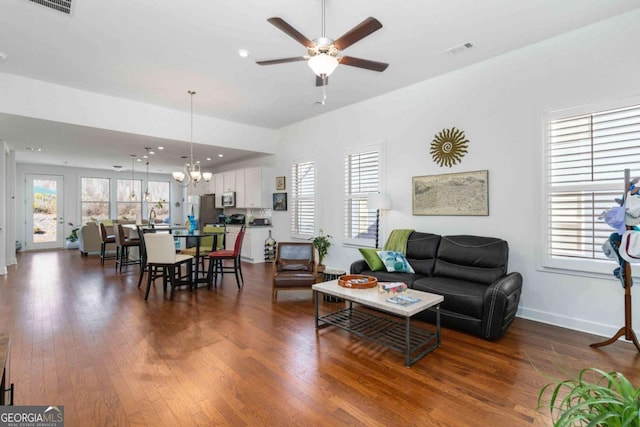 living room with dark wood-type flooring and ceiling fan with notable chandelier