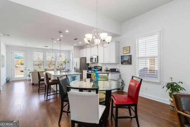 dining room with a wealth of natural light, sink, dark wood-type flooring, and a chandelier