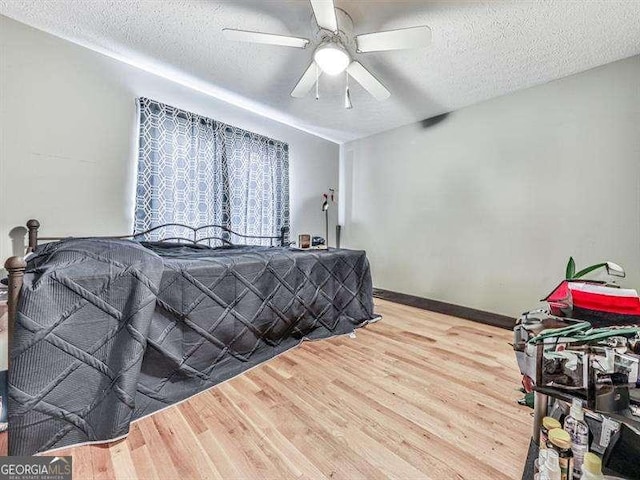 bedroom with hardwood / wood-style floors, a textured ceiling, and ceiling fan