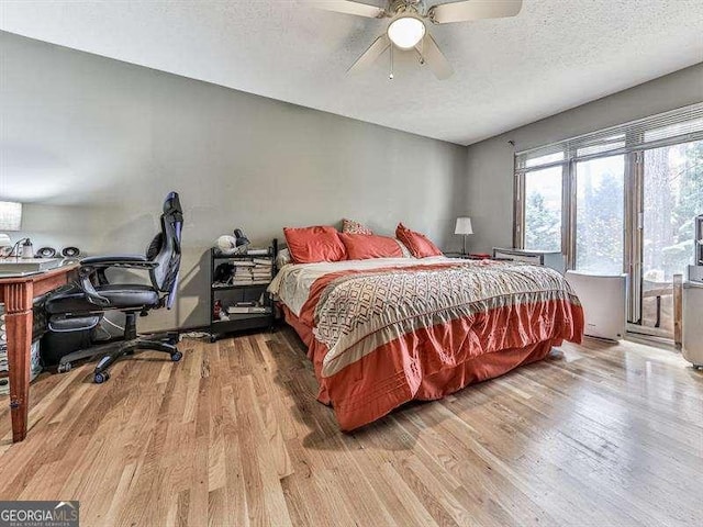 bedroom with ceiling fan, light hardwood / wood-style flooring, and a textured ceiling