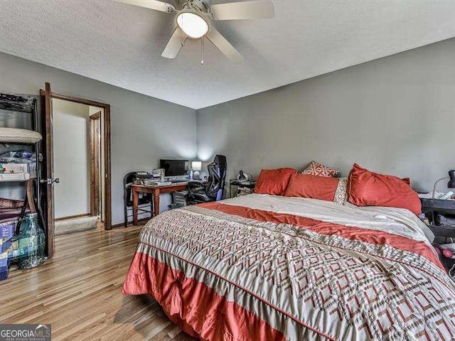 bedroom featuring ceiling fan, hardwood / wood-style floors, and a textured ceiling