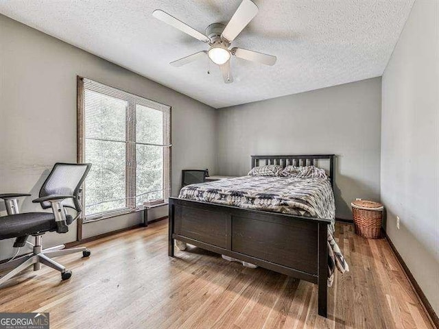 bedroom featuring ceiling fan, a textured ceiling, and light wood-type flooring