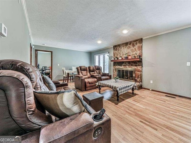 living room with hardwood / wood-style flooring, ornamental molding, a textured ceiling, and a fireplace