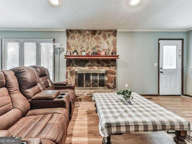 living room with crown molding, a fireplace, light hardwood / wood-style floors, and a textured ceiling