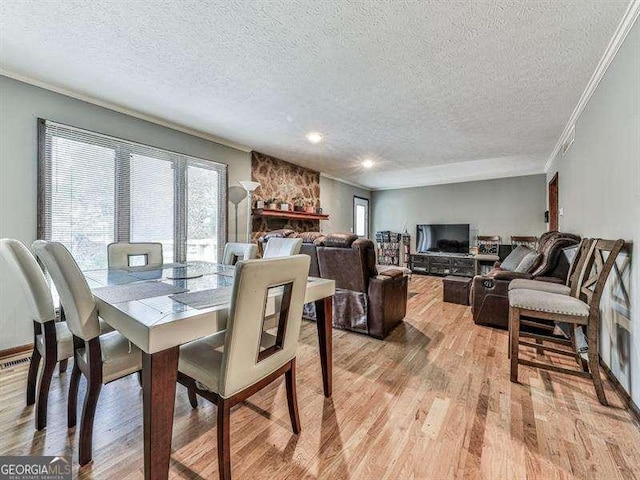 dining room featuring light hardwood / wood-style flooring, ornamental molding, and a textured ceiling