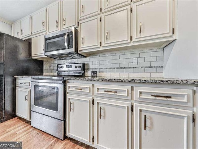 kitchen with white cabinetry, appliances with stainless steel finishes, stone countertops, and decorative backsplash