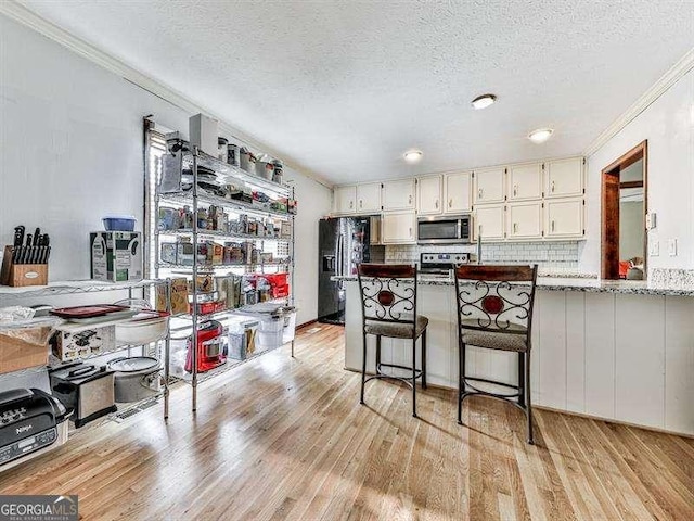 kitchen with stainless steel appliances, light stone counters, light wood-type flooring, and decorative backsplash