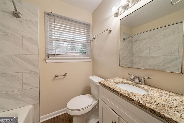 full bathroom with hardwood / wood-style flooring, vanity, tiled shower / bath combo, and toilet