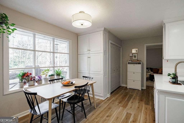 dining area with a textured ceiling and light hardwood / wood-style floors