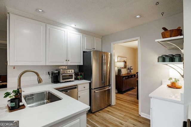 kitchen featuring appliances with stainless steel finishes, sink, white cabinets, and light hardwood / wood-style floors