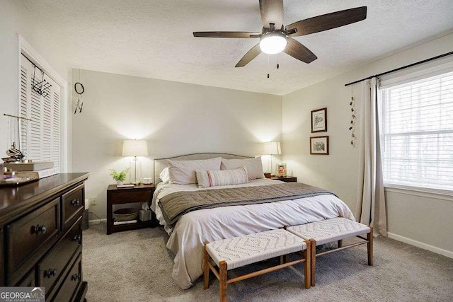 bedroom featuring ceiling fan, light carpet, and a textured ceiling