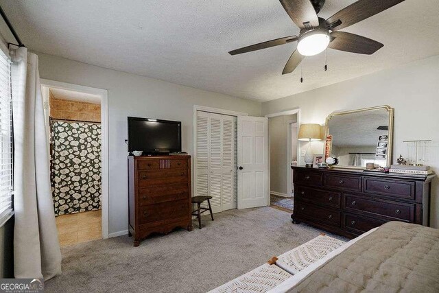 carpeted bedroom with ceiling fan, connected bathroom, a textured ceiling, and a closet