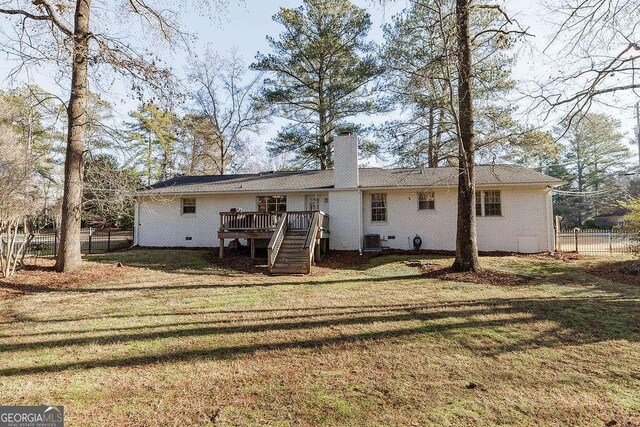 rear view of property featuring a wooden deck, central AC, and a lawn