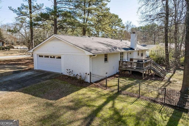 exterior space featuring a garage, a deck, and a lawn