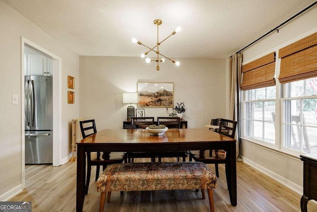 dining room with a notable chandelier, light hardwood / wood-style floors, and a textured ceiling